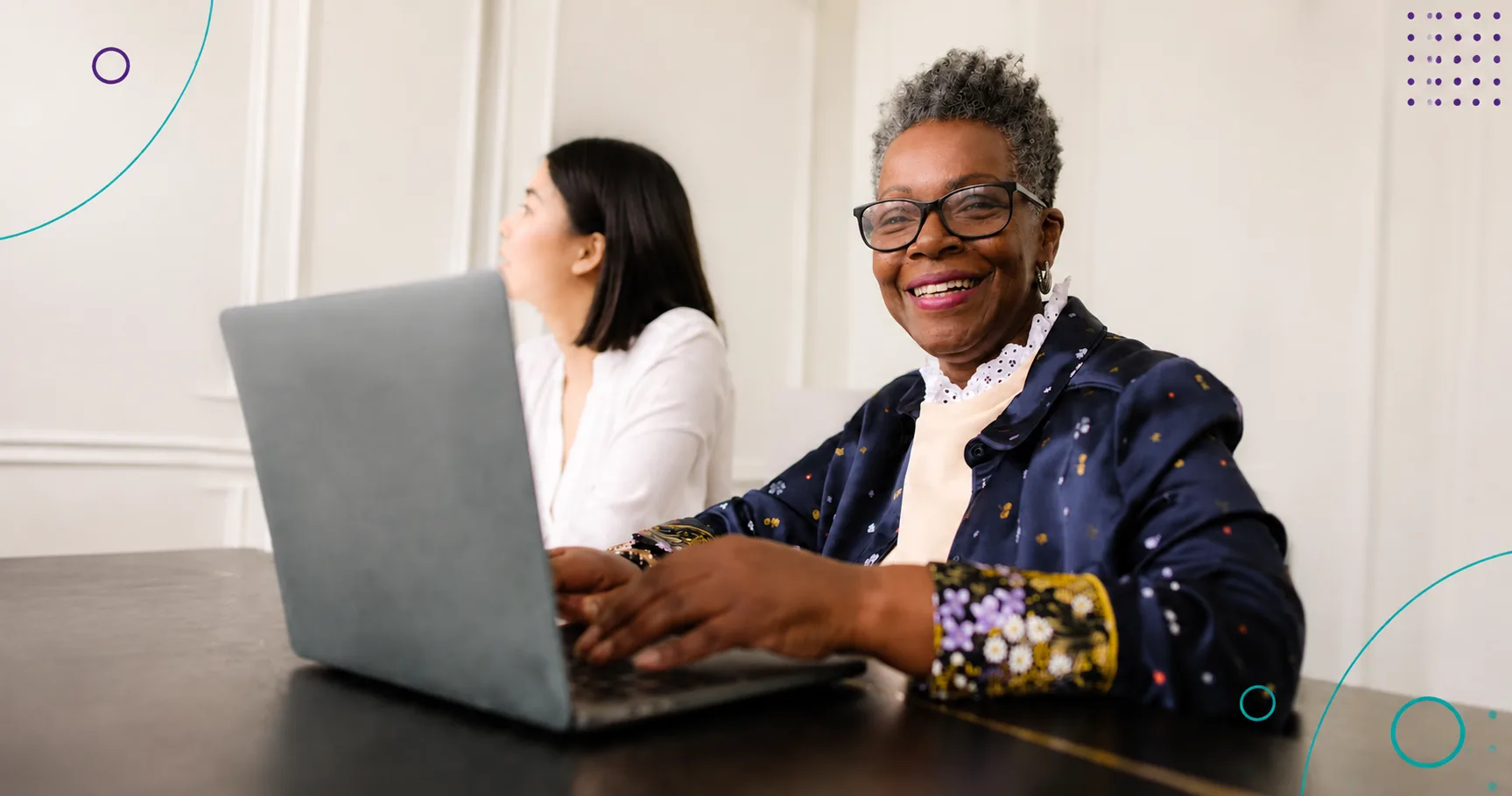 Smiling older Black woman using a laptop in a well-lit room